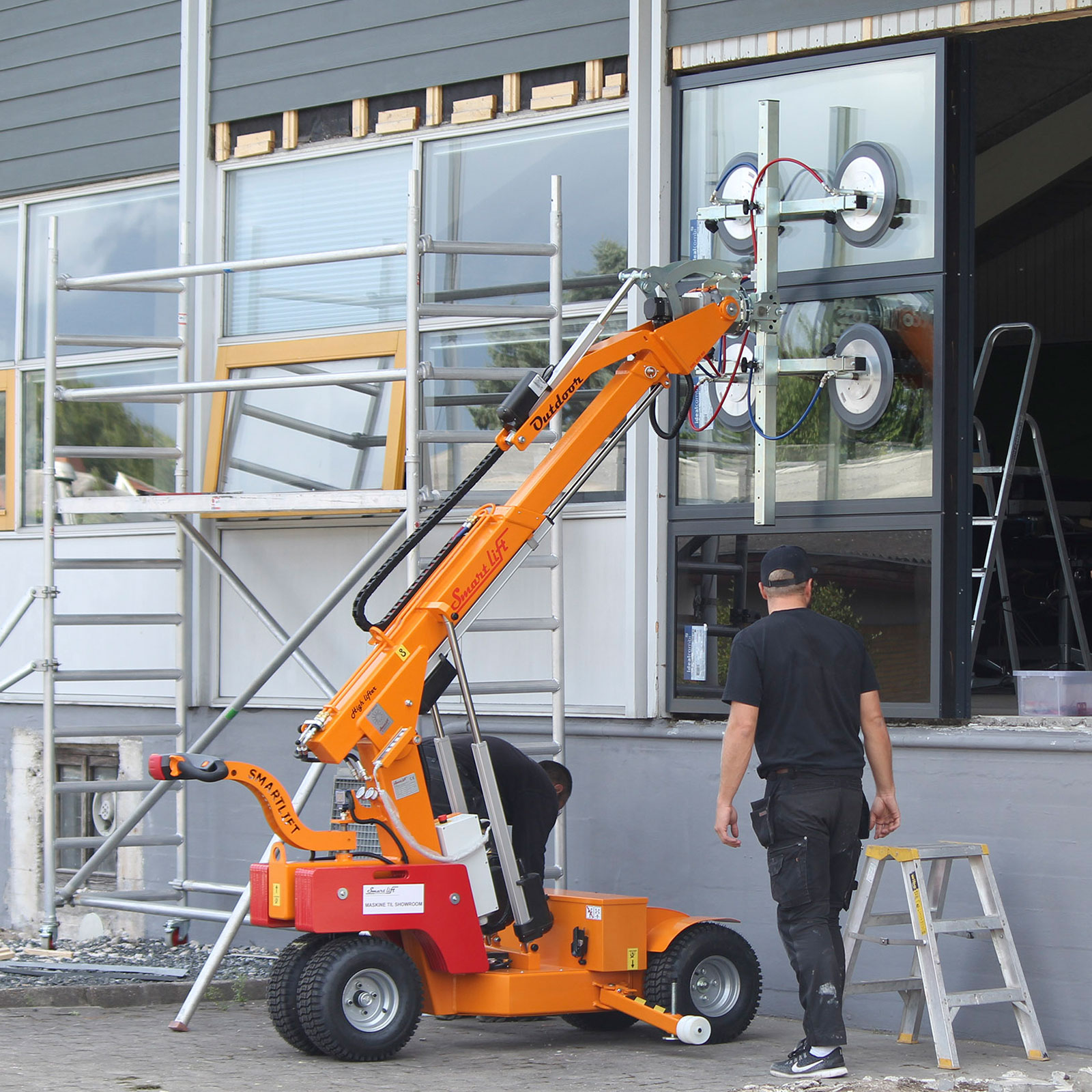 Der Mietkran "Smartlift" im Einsatz wie er eine Glasscheibe an ihren Platz hebt.
