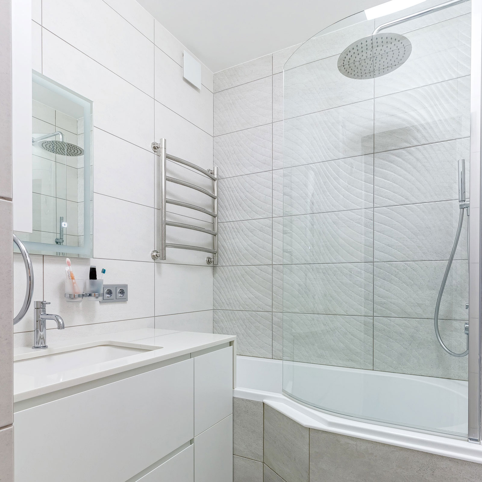Ein helles Badezimmer mit Badewanne, die von einer Glaswand geschützt wird.